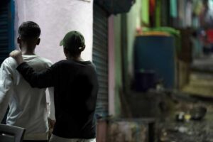 Boy with arm around his friend looking away from camera