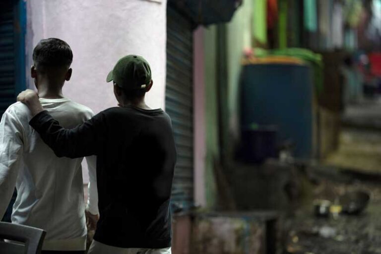Boy with arm around his friend looking away from camera