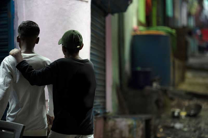 Boy with arm around his friend looking away from camera